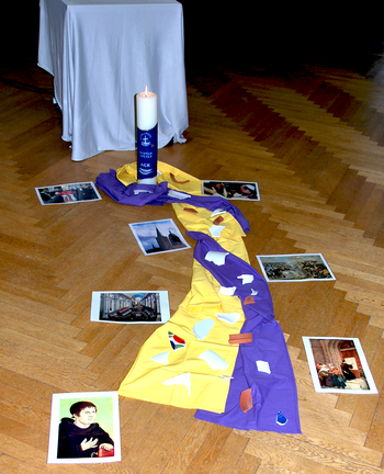 Erwachsenenbildung Ein Bodenbild aus gelben und violetten Tüchern mit Bilden zu ökumenischen Themen, das bei einer Bildungsveranstaltung die Mitte eines Stuhlkreises bildet.